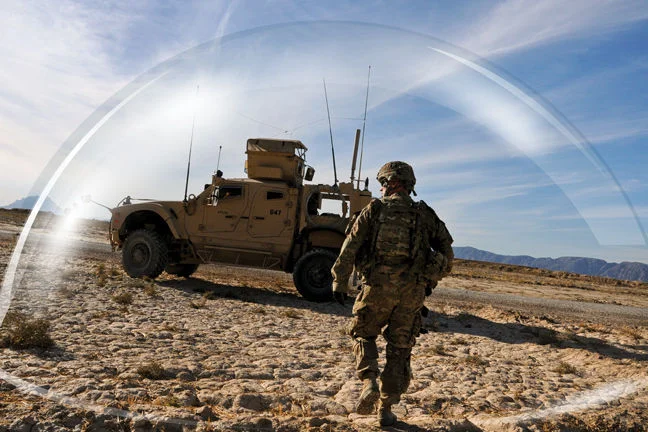 A man in military gear approaching a vehichle. There is a opaque dome around him and the vehicle. 